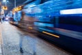 The tram leaves the stop in night city, motion blur view