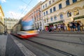 Tram with motion blur passing waiting pasengers at a tram station in the old town district of Prague Royalty Free Stock Photo