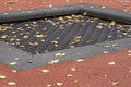 Trampoline covered with autumn yellow leaves at open air children playground Royalty Free Stock Photo