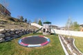 Trampoline and a slide in a green fenced area