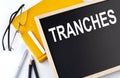 TRANCHES text on the blackboard with notepad , pen, pencil Royalty Free Stock Photo