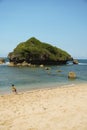 A tranquil beach scene in Gunungkidul, featuring white sands, clear waters, and offshore rock formations