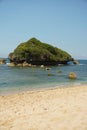 A tranquil beach scene in Gunungkidul, featuring white sands, clear waters, and offshore rock formations