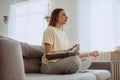 Blonde woman with stylish prosthesis arm meditates on sofa