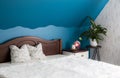 Tranquil blue color bedroom concept. Air cleaning plant Spathiphyllum on flower stand Amethyst crystal lamp illuminated.