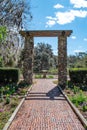 Tranquil brick pathway lined with lush foliage leads to a picturesque park