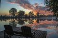 Tranquil colorful sunset at lake with benches on coast