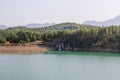 Tranquil Forest Lake with Rocky Waterfall and Mountainous Horizon