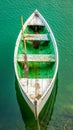 Tranquil Green and White Rowboat Floating on Crystal Clear Water in Serene Lake Setting Perfect for Nature and Outdoor Enthusiasts