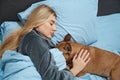 Tranquil lady and her dog resting together in bedroom Royalty Free Stock Photo