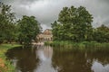 Tranquil lake with lawn, grove. building and cloudy sky in Amsterdam park.