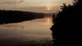 Tranquil lake scene with majestic pine trees silhouetted against a golden sky at sunset Royalty Free Stock Photo