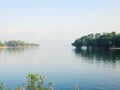 Tranquil Lakeside View Featuring Reflections of Trees and Islands on Calm Waters Under a Clear Sky Royalty Free Stock Photo