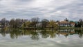 Tranquil landscape with lake, houses, cloudy sky, and trees reflected symmetrically in the water. Nyiregyhaza, Hungary Royalty Free Stock Photo