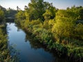 Tranquil landscape of a riverbank featuring a slow, steady flow of water surrounded by vegetation Royalty Free Stock Photo