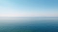 Tranquil minimalist landscape with a smooth blue sea surface with calm waters with a horizon and clear skies.