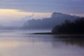 Tranquil Misty morning layered landscape of trees reflected in a still lake