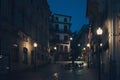 Tranquil, night-time scene of a deserted street, featuring benches, tables and lampposts