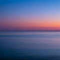 Tranquil ocean scene during twilight, capturing a gradient sky shifting from warm