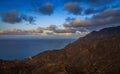 Tranquil ocean view overlooking a hillside with picturesque clouds at sunset