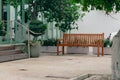 Tranquil outdoor seating area with a wooden bench in Neve Tzedek, Tel Aviv, surrounded by lush greenery and a quaint white Royalty Free Stock Photo