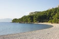 A tranquil pebble beach curves along the clear blue sea in Makarska, Croatia, with lush pines and mountains Royalty Free Stock Photo