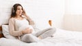 Tranquil pregnant woman listening to music with wireless headphones