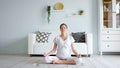 Tranquil pregnant woman meditates in lotus pose at home