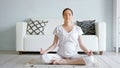 Tranquil pregnant woman meditates in lotus pose at home