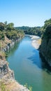 A tranquil river flows gently between steep, green-sided canyons, reflecting the bright blue sky, making for a peaceful Royalty Free Stock Photo