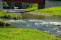 Beautiful River Flowing Beneath a Red Covered Bridge in a Serene Landscape During a Sunny Day Royalty Free Stock Photo