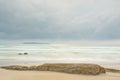 Tranquil scene of a beach at the sea with an island in the background and rocks in the foreground Royalty Free Stock Photo