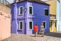 Tranquil scene with a couple of tourists strolling along the colorful houses in Burano island, Venice