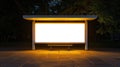A tranquil scene at dusk, an empty bus stop poster display illuminated by warm lights, surrounded by urban trees Royalty Free Stock Photo