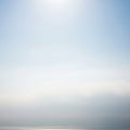 A tranquil scene features a clear blue sky with a bright sun at the top. Below, a stretch of calm Royalty Free Stock Photo