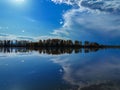 Tranquil scene of a lake surrounded by trees, with a clear blue sky with wispy clouds Royalty Free Stock Photo