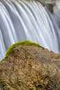 Tranquil scene of nature in the woods featuring a moss-covered rock with a waterfall cascading over Royalty Free Stock Photo