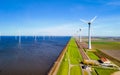 A tranquil scene of a row of windmills standing tall next to a calm lake in Flevoland, Netherlands Royalty Free Stock Photo
