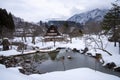 In the tranquil setting of Shirakawa village, the reflection of a snow-thatched roof cottage is beautifully mirrored in a small Royalty Free Stock Photo