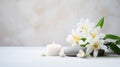 A tranquil spa still life with a white flower arrangement, two candles, and massage stones on a white background Royalty Free Stock Photo