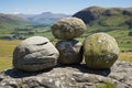 Tranquil stone stacking on green grass under clear blue sky with play of light and shadow