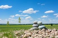Tranquil stone stacks in a serene scene against lush green grass and clear blue sky