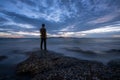 Tranquil stony bay with a rear of man after sunset. Slow shutter speed for smooth water level and dreamy effect. Royalty Free Stock Photo