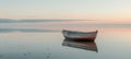 Tranquil sunset seascape with empty wooden rowboat on calm waters under serene skies