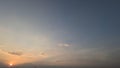 A tranquil sunset sky featuring a soft gradient from blue to orange and gold. The bright sun peeks from behind light clouds Royalty Free Stock Photo