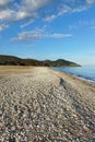 Tranquil Sunset View Pebble Beach Stretching to Distant Mountains under Blue Sky Royalty Free Stock Photo