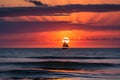 Tranquil Twilight: Sunset Cascading Over an Undulating Ocean, Distant Silhouette of a Solitary Sailboat on the Horizon Royalty Free Stock Photo