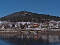 View of Schluchsee village with railway bridge reflected on the frozen lake and observation tower on hill in winter. Royalty Free Stock Photo