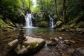 Serene Waterfall in Lush Forest with Stone Cairn Royalty Free Stock Photo