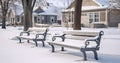 A Tranquil Winter Landscape with Vacant Benches in a Park Surrounded by Snow-Cloaked Buildings and Homes
